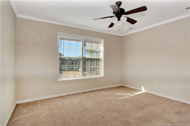 carpeted empty room with ceiling fan, visible vents, baseboards, and crown molding