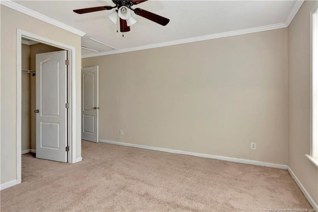 spare room featuring ceiling fan, carpet floors, baseboards, attic access, and crown molding