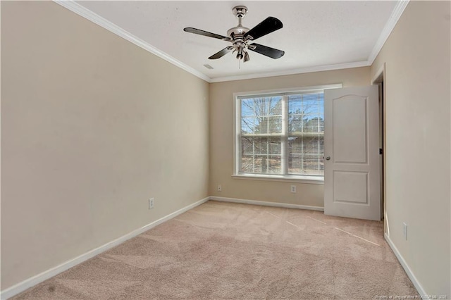 spare room with baseboards, ornamental molding, and light colored carpet