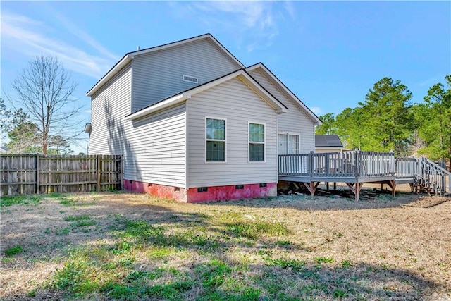 back of house featuring crawl space, fence, a deck, and a lawn