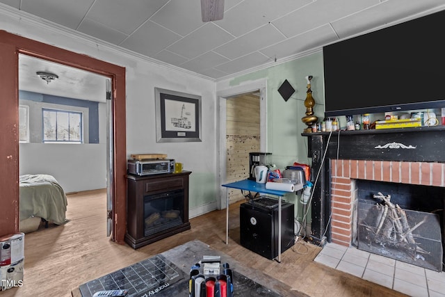 living area featuring a brick fireplace, wood finished floors, and crown molding