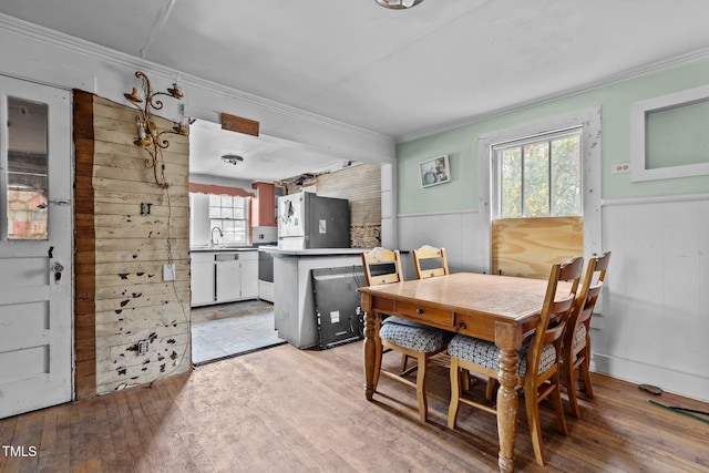 dining area featuring a wainscoted wall, light wood finished floors, and ornamental molding