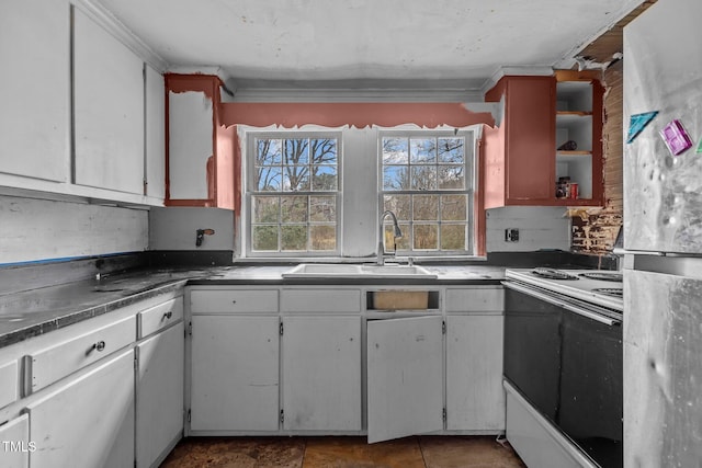 kitchen with a sink, white cabinets, freestanding refrigerator, and electric stove