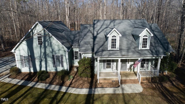 cape cod-style house featuring covered porch and a tiled roof