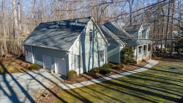 view of side of property with a garage, roof with shingles, a lawn, and gravel driveway