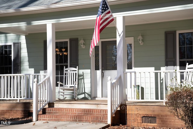 doorway to property featuring a porch, crawl space, and a shingled roof