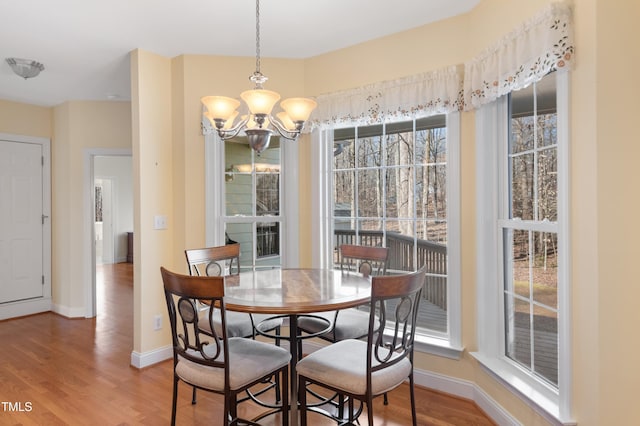 dining area featuring a chandelier, baseboards, and wood finished floors