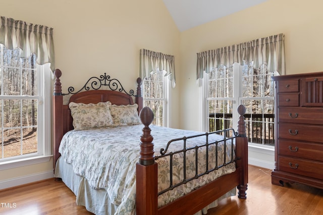 bedroom with baseboards, vaulted ceiling, and wood finished floors