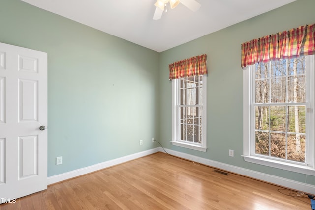 empty room featuring a healthy amount of sunlight, baseboards, and wood finished floors