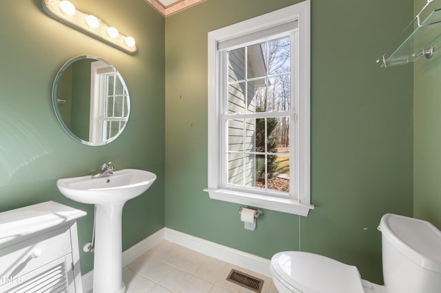 bathroom featuring visible vents, toilet, a sink, baseboards, and tile patterned floors