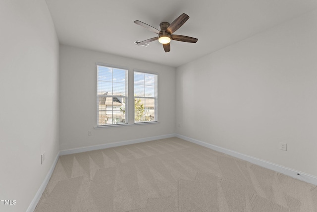 empty room featuring light carpet, a ceiling fan, and baseboards