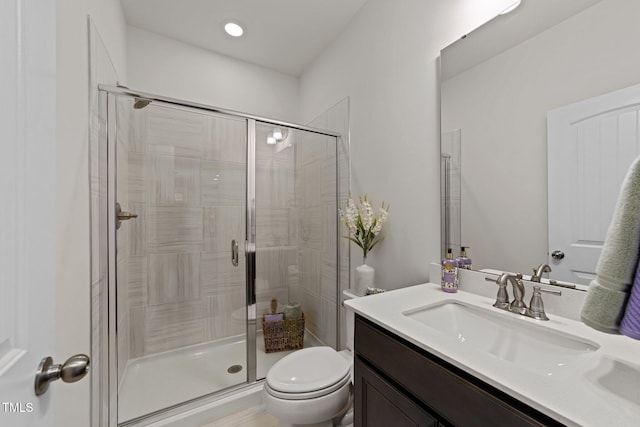 bathroom with toilet, a stall shower, and vanity