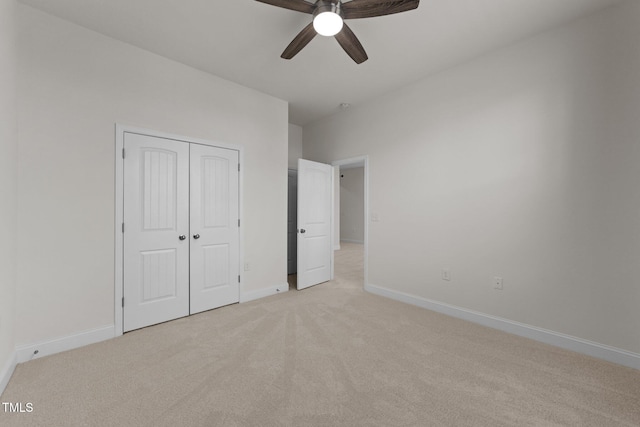 unfurnished bedroom featuring a closet, light colored carpet, baseboards, and ceiling fan