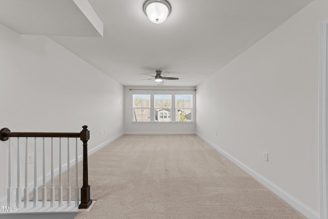 carpeted spare room featuring baseboards and ceiling fan