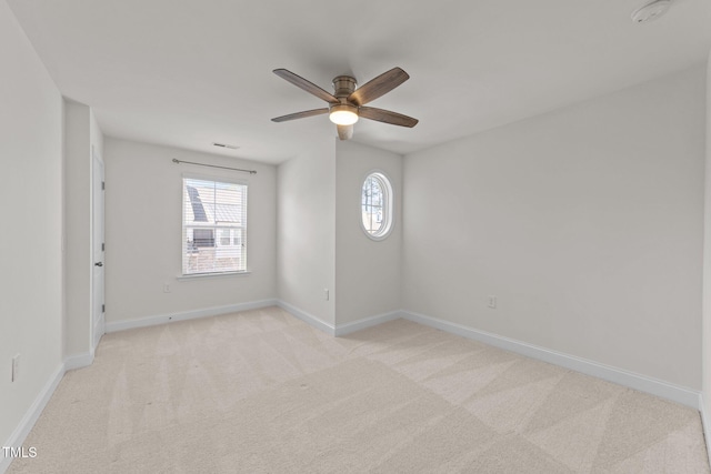 empty room with visible vents, baseboards, light colored carpet, and ceiling fan