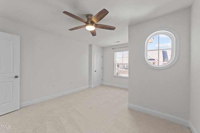 empty room featuring light colored carpet, baseboards, and ceiling fan