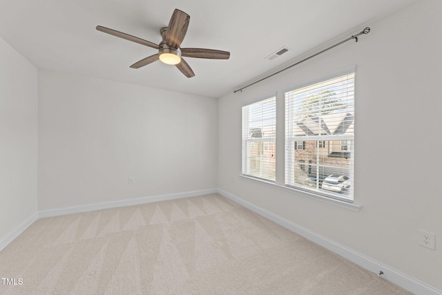 spare room with visible vents, light colored carpet, a ceiling fan, and baseboards