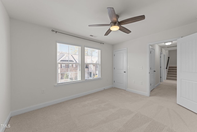 unfurnished bedroom featuring light carpet, visible vents, ceiling fan, and baseboards