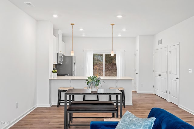 dining area with baseboards, visible vents, wood finished floors, and recessed lighting