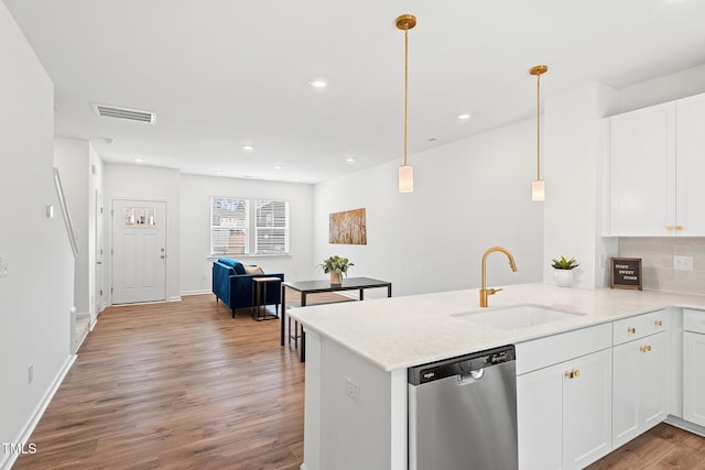 kitchen with visible vents, dishwasher, wood finished floors, a peninsula, and a sink