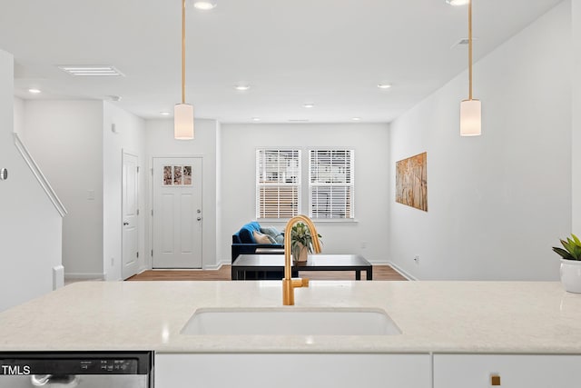 kitchen with open floor plan, stainless steel dishwasher, a sink, and decorative light fixtures