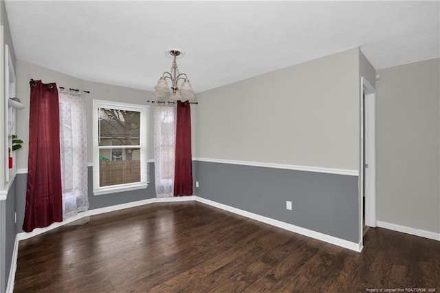 spare room featuring an inviting chandelier, wood finished floors, and baseboards