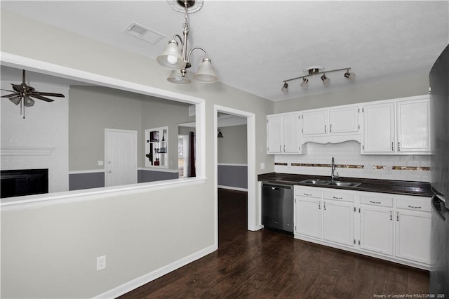 kitchen featuring visible vents, stainless steel dishwasher, dark wood-type flooring, white cabinets, and a sink