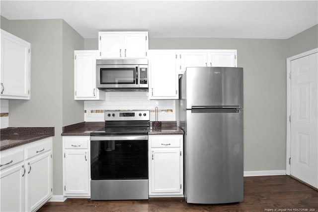 kitchen with appliances with stainless steel finishes, white cabinets, and tasteful backsplash