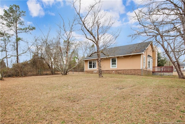 view of home's exterior featuring a yard, a wooden deck, and fence