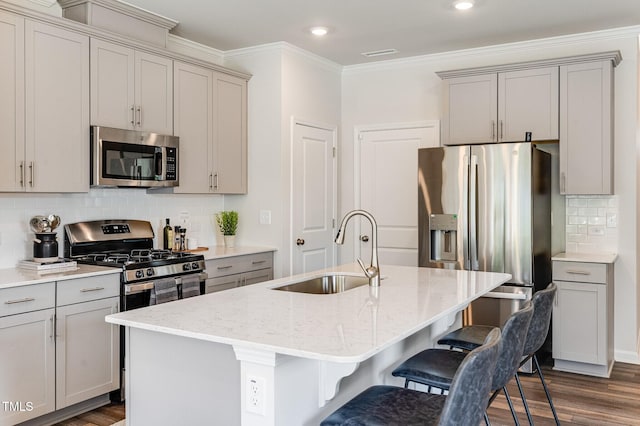 kitchen featuring stainless steel appliances, gray cabinets, a sink, and a breakfast bar area