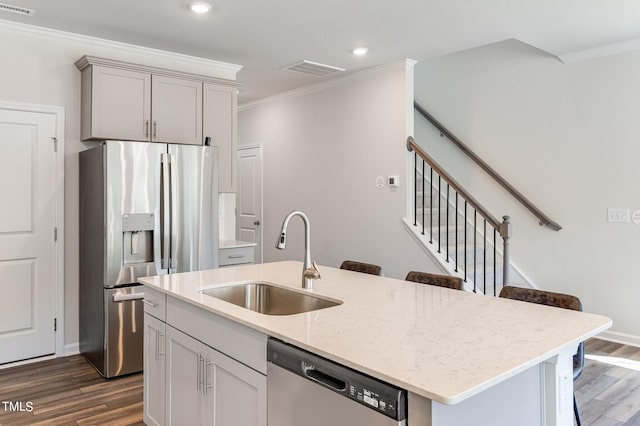 kitchen featuring stainless steel appliances, a sink, visible vents, ornamental molding, and dark wood finished floors