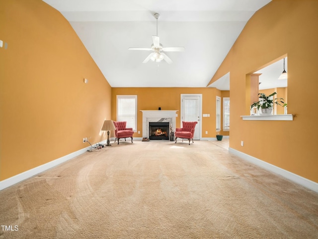 sitting room featuring carpet, a fireplace, a healthy amount of sunlight, high vaulted ceiling, and baseboards