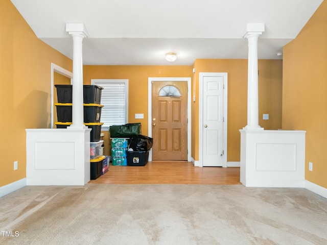 entrance foyer with light carpet, ornate columns, and baseboards