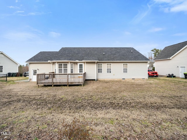 rear view of property with crawl space, a deck, a lawn, and roof with shingles