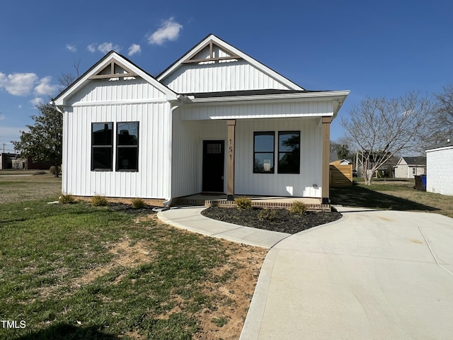 modern farmhouse style home with a porch, a front yard, and board and batten siding