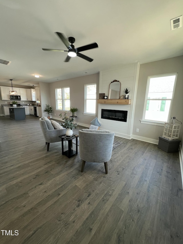 living area with plenty of natural light, visible vents, and a glass covered fireplace