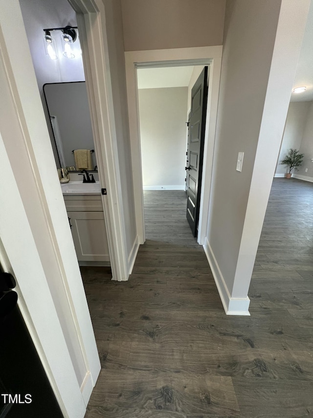 corridor with a sink, dark wood finished floors, and baseboards