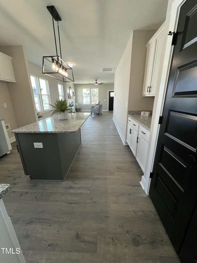 kitchen with dark wood-style floors, a kitchen island, white cabinetry, and open floor plan