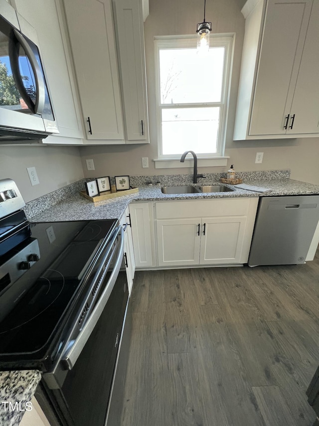 kitchen with dark wood-style flooring, decorative light fixtures, stainless steel appliances, white cabinetry, and a sink