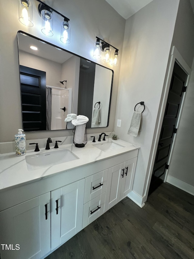 bathroom featuring double vanity, wood finished floors, a sink, and curtained shower