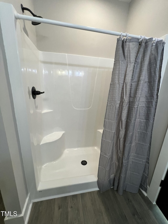 full bathroom with a stall shower and wood finished floors