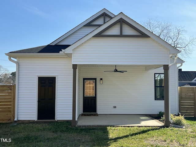 rear view of house with ceiling fan, fence, a shingled roof, and a patio