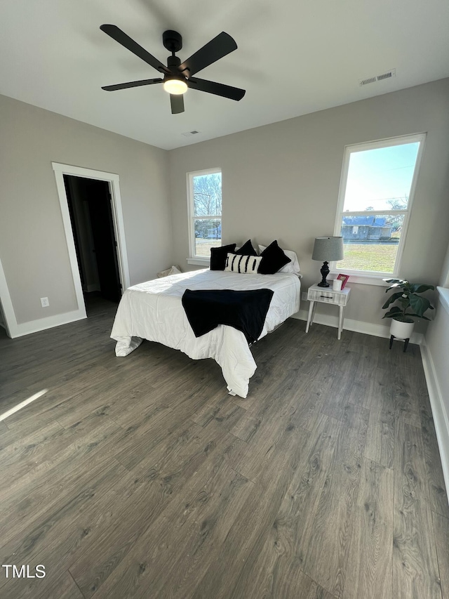 bedroom featuring a ceiling fan, dark wood finished floors, visible vents, and baseboards