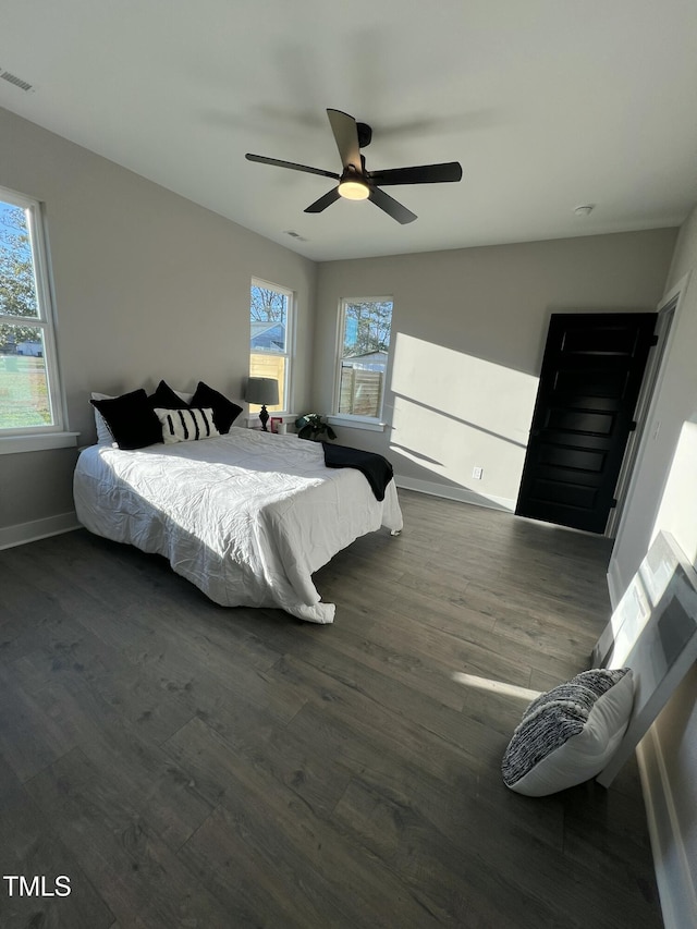 bedroom featuring baseboards, wood finished floors, visible vents, and a ceiling fan