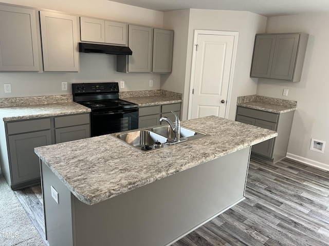 kitchen featuring black range with electric stovetop, under cabinet range hood, gray cabinets, wood finished floors, and a sink