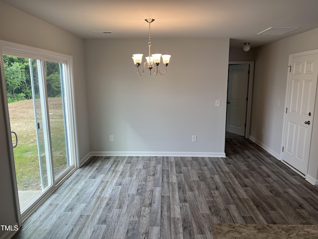 unfurnished room featuring a notable chandelier, visible vents, baseboards, and wood finished floors