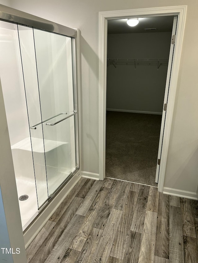 full bath with a shower stall, baseboards, and wood finished floors