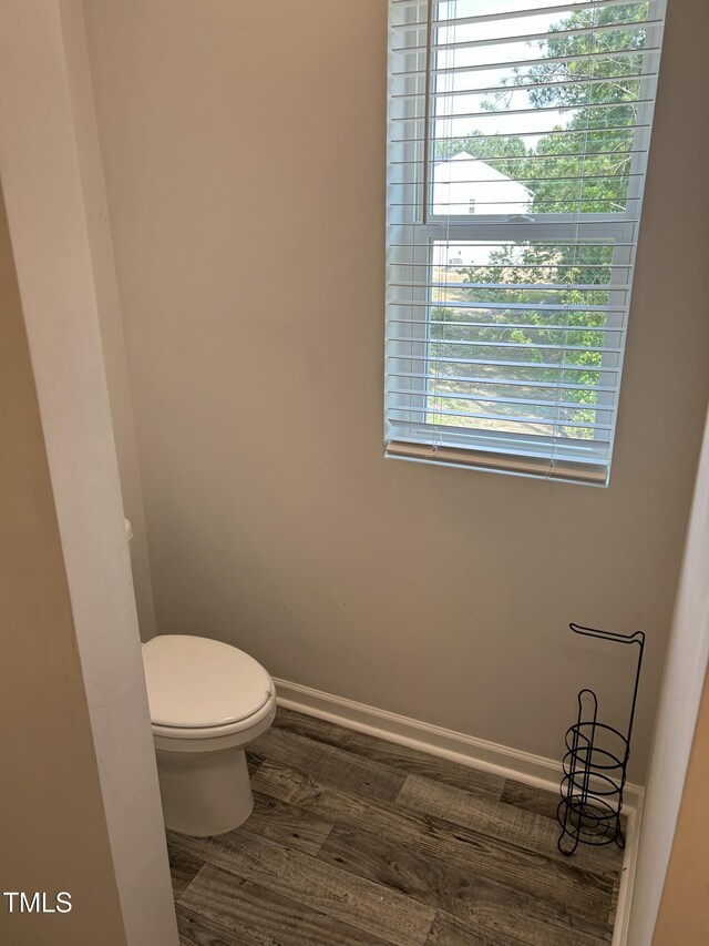 bathroom featuring toilet, wood finished floors, plenty of natural light, and baseboards