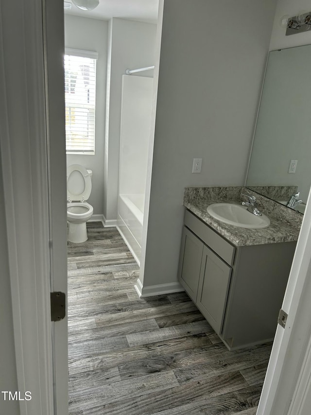 full bathroom with toilet, vanity, baseboards, and wood finished floors