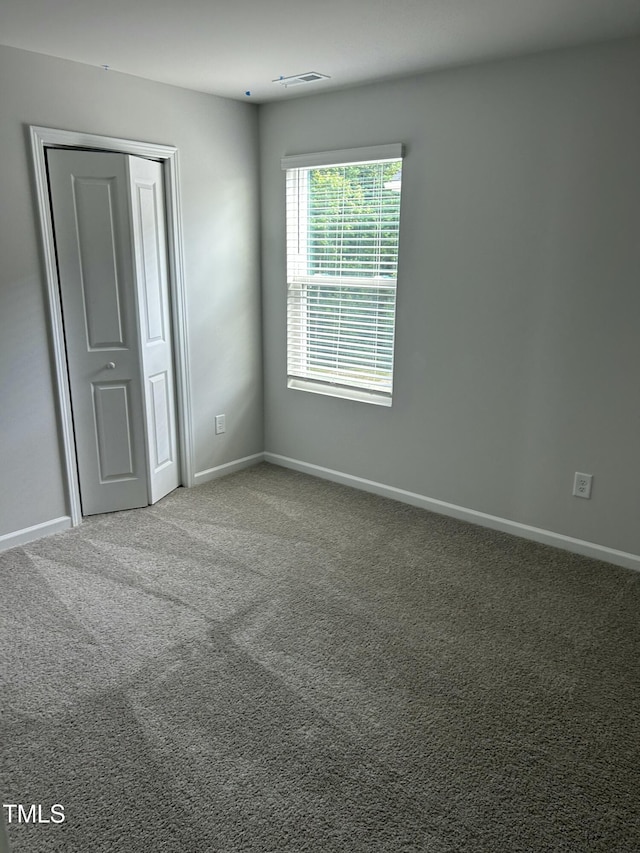 unfurnished bedroom featuring carpet flooring, baseboards, visible vents, and a closet